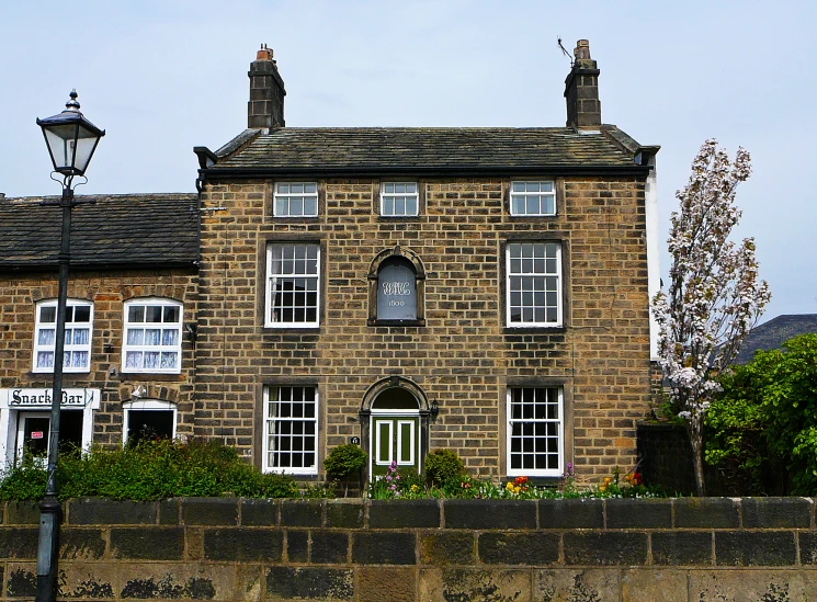 an old brick building with three windows near a stone wall