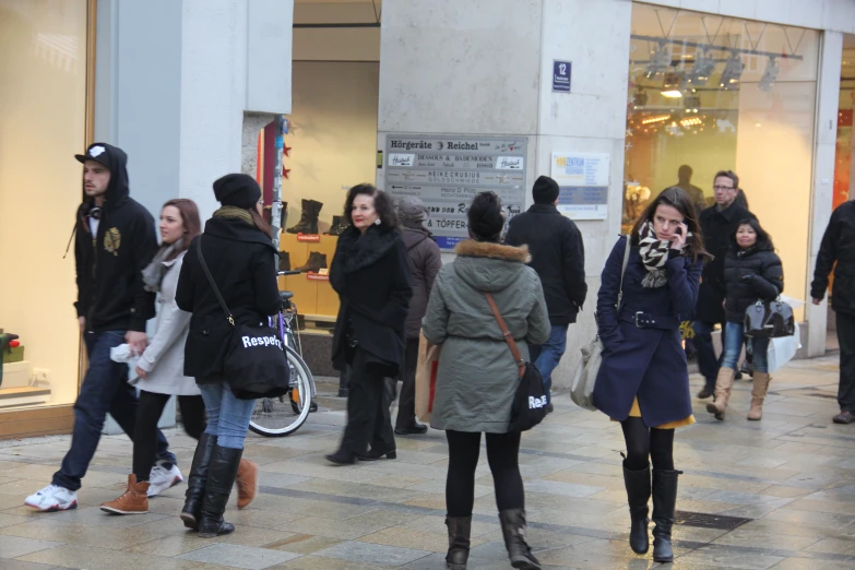 people walking down the street near a store with clothes on it