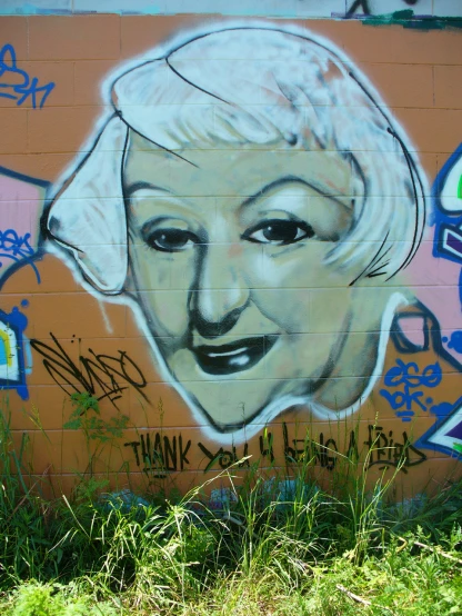 a large portrait of a lady with short hair on the side of a brick wall