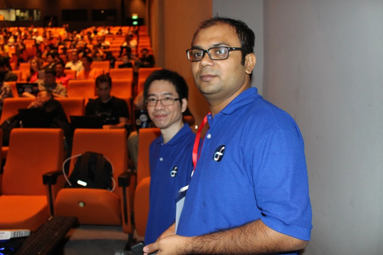 two men in blue shirts are looking at soing