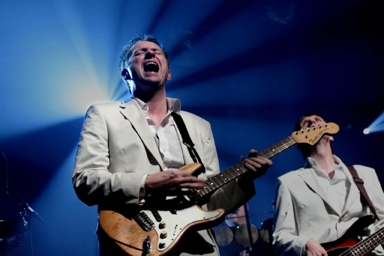 a couple of men are playing guitars and singing