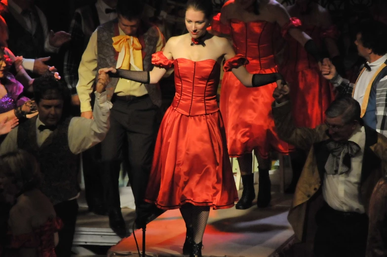 a woman wearing a red dress walks on a catwalk