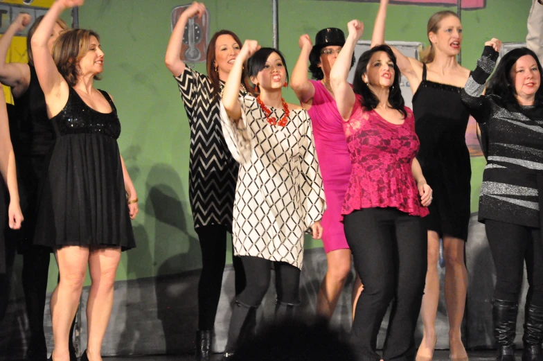 the young women are dancing together on stage