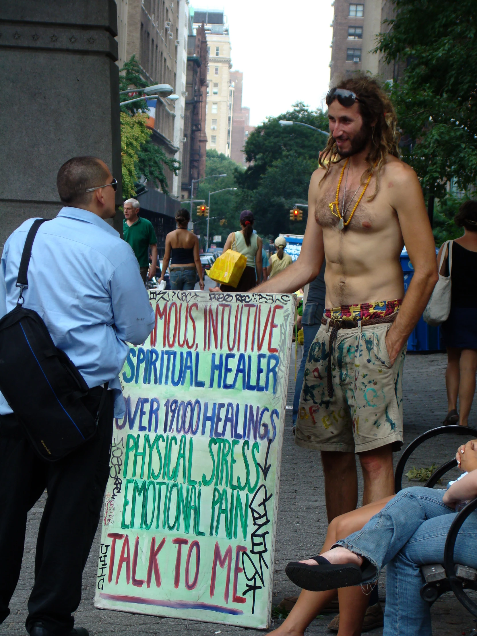 a man holding a sign on the sidewalk while standing in front of people