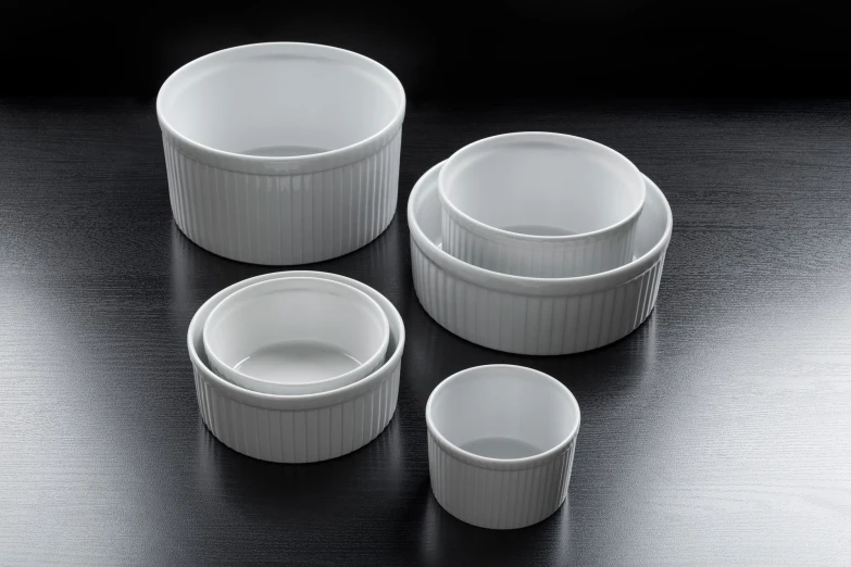 five white dishes stacked next to each other on a black surface