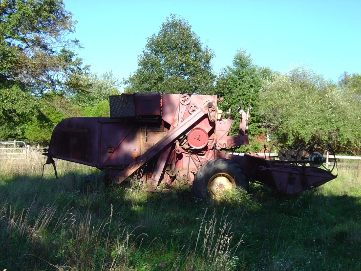 an old truck sitting in a field near a fence