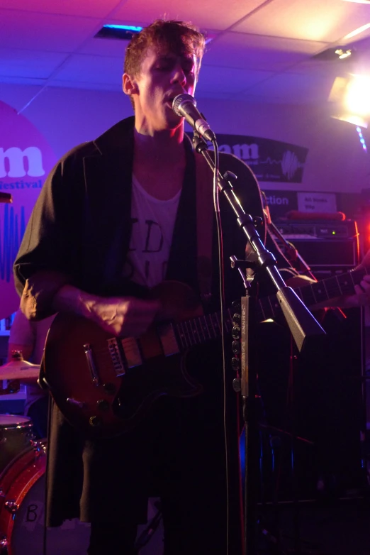 a man with a guitar standing in front of a microphone