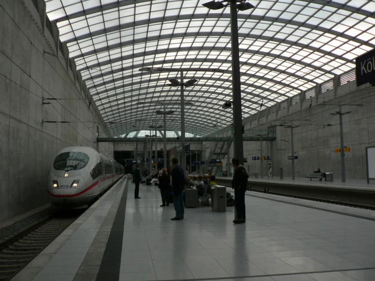 the people walk in line on the platform as a train passes by