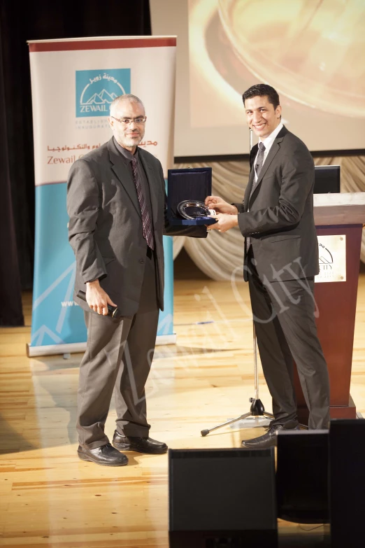 a man standing next to another man on stage