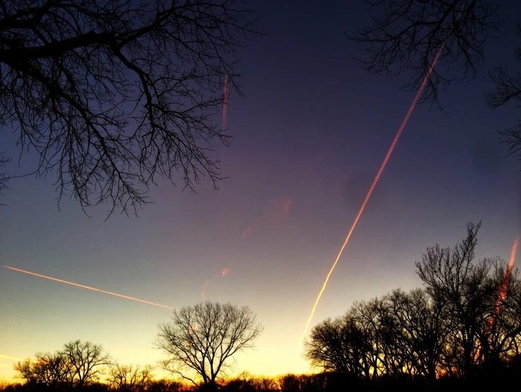 two airplanes flying through the sky at dusk