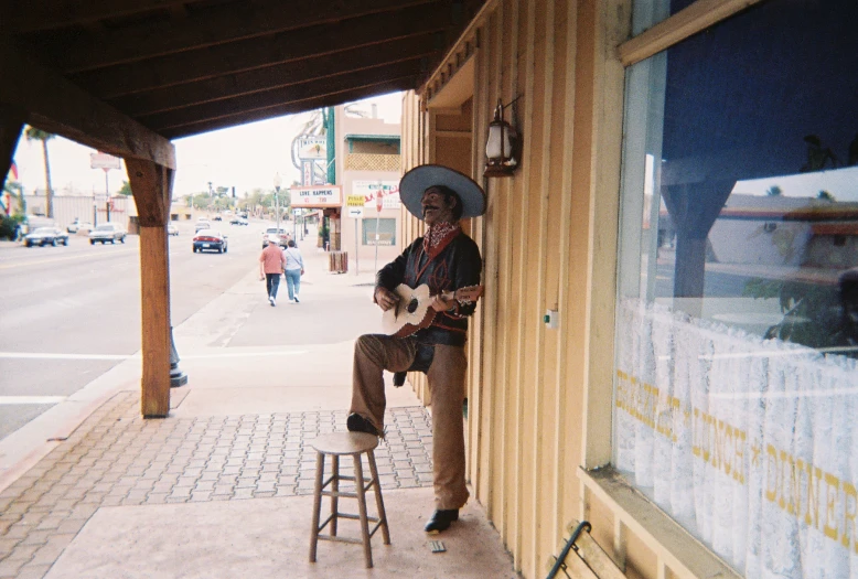 a man with a guitar leaning against a wall