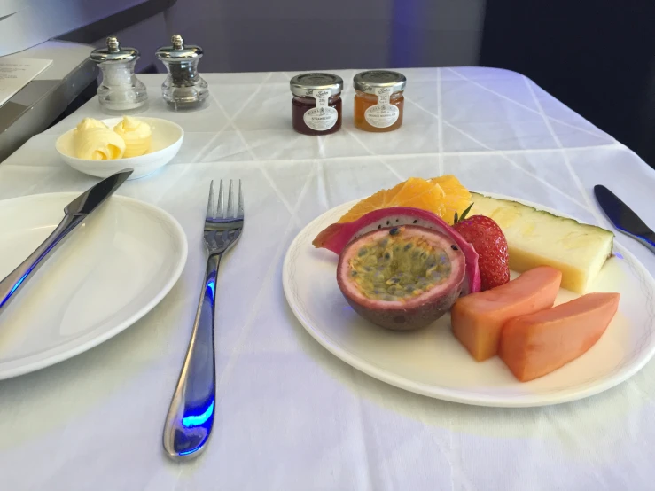 plates and silverware on the table with fruit and ers