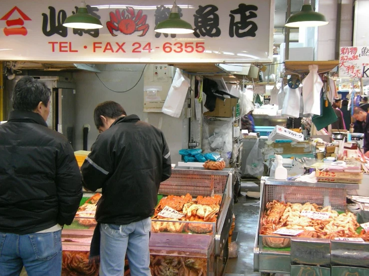 a group of men standing around a large fish market