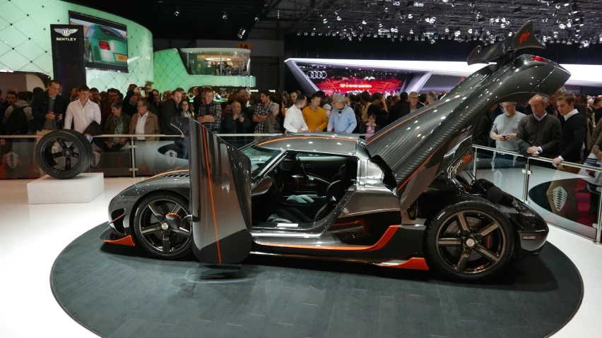 people at an auto show in front of a futuristic vehicle