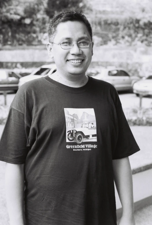 a man in glasses poses for a black and white po