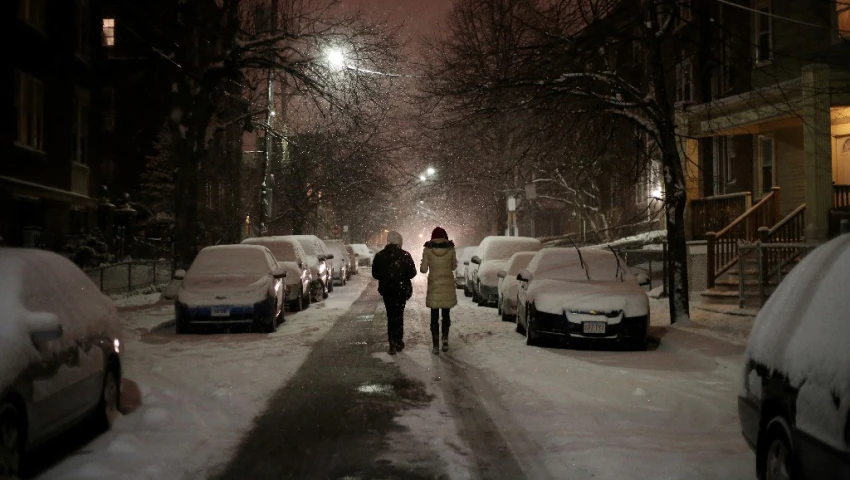 two people walking down a snowy city street at night