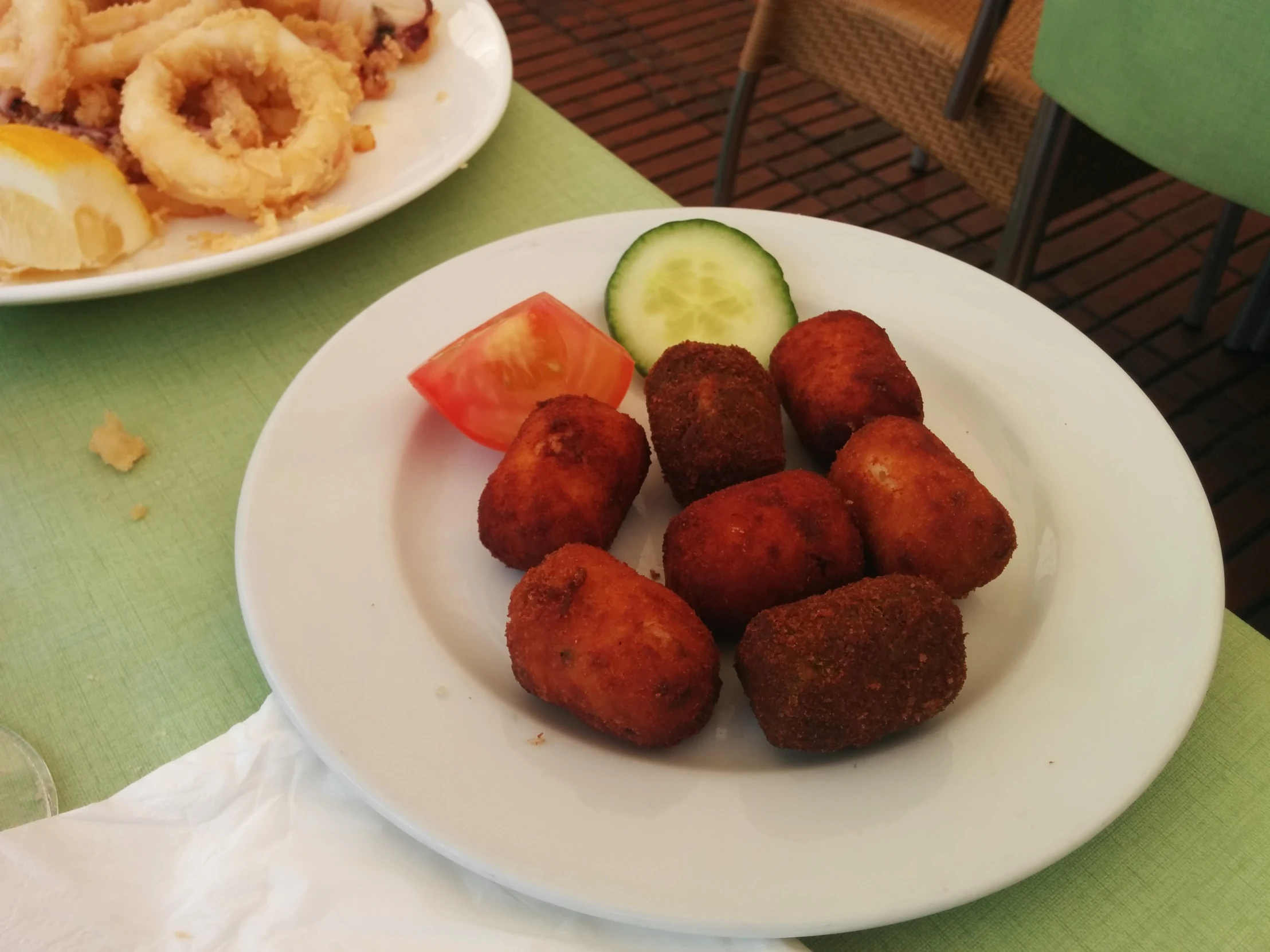 a white plate topped with cooked food next to a bowl of onion rings