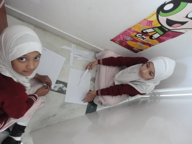 a girl and boy holding up papers in front of him