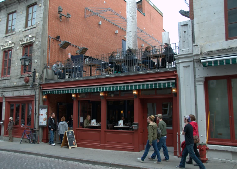 people walking on the sidewalk in front of a building