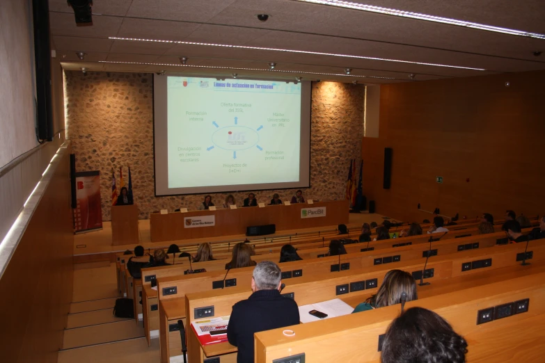 audience at podium in front of screen with large audience