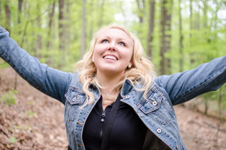 a young blonde woman poses in front of a wooded area