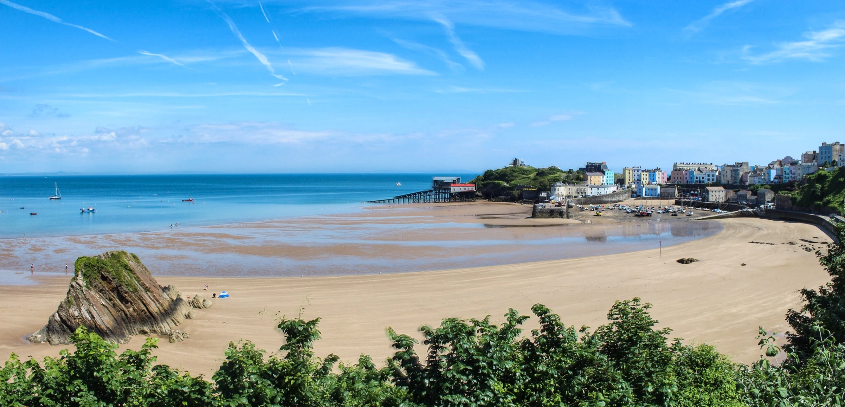 a sandy beach with a body of water and small boats on it