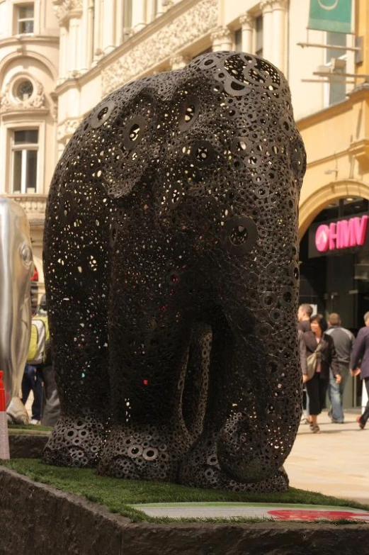 the sculpture is near many people standing in the street