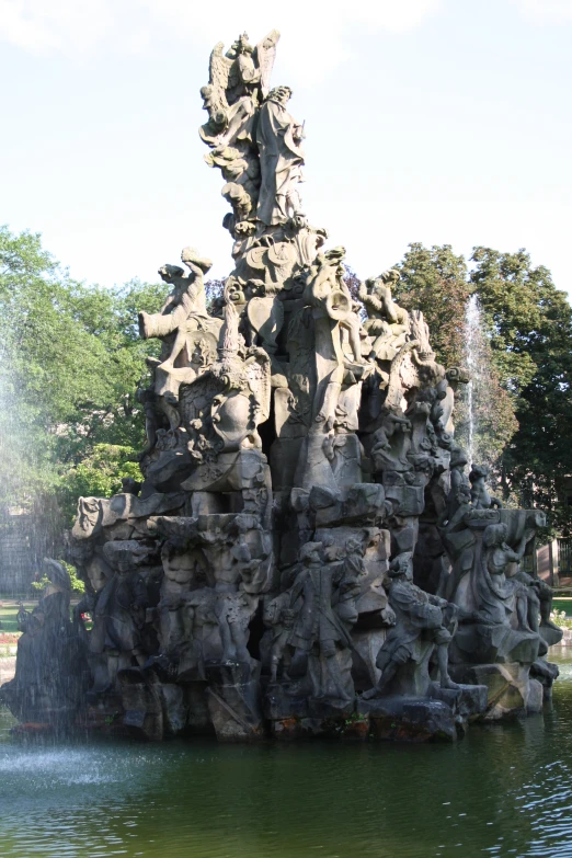 many different statues near a fountain in a park