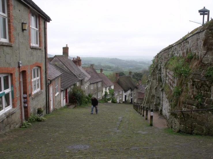 a lone man walking down a cobbled stone street