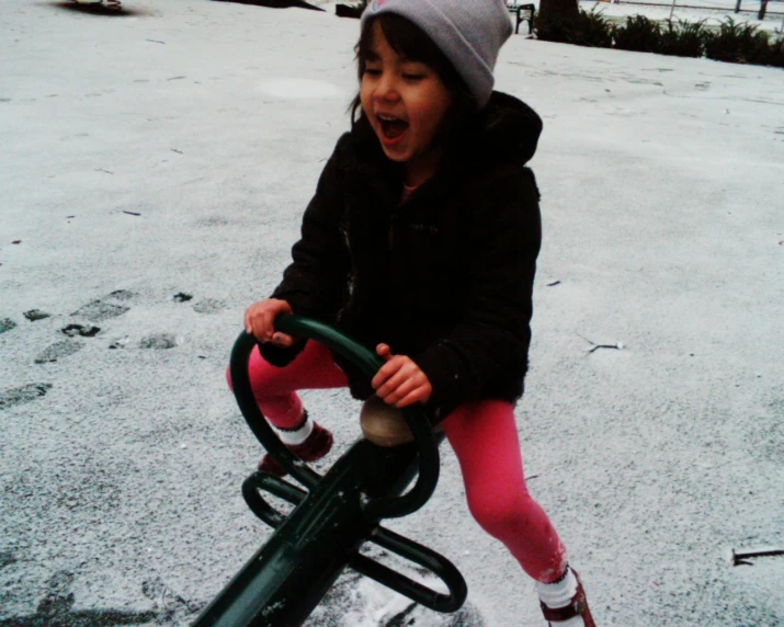 a little girl playing in the playground in the snow