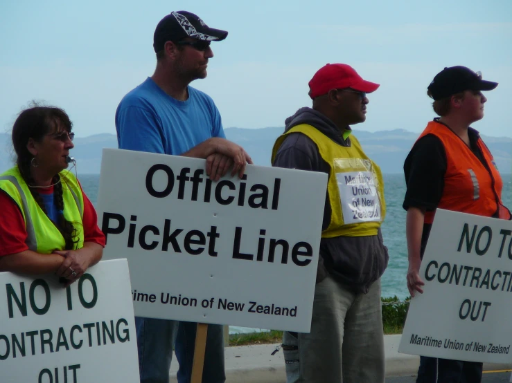 people standing on the beach holding up signs