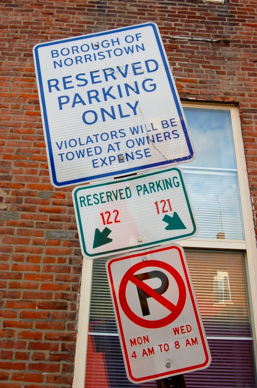 a three way parking sign on a brick building