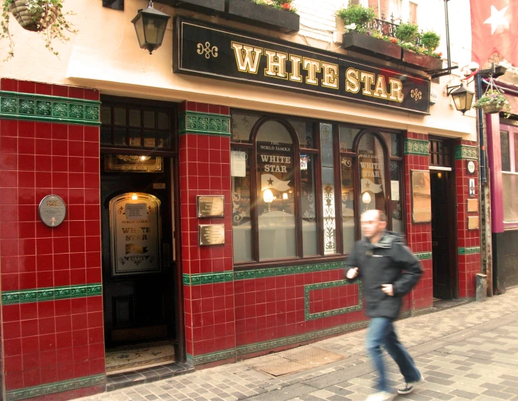 a man in a black jacket is walking by a white star restaurant