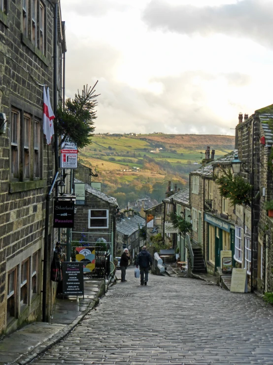 people walk down an old cobble stone road