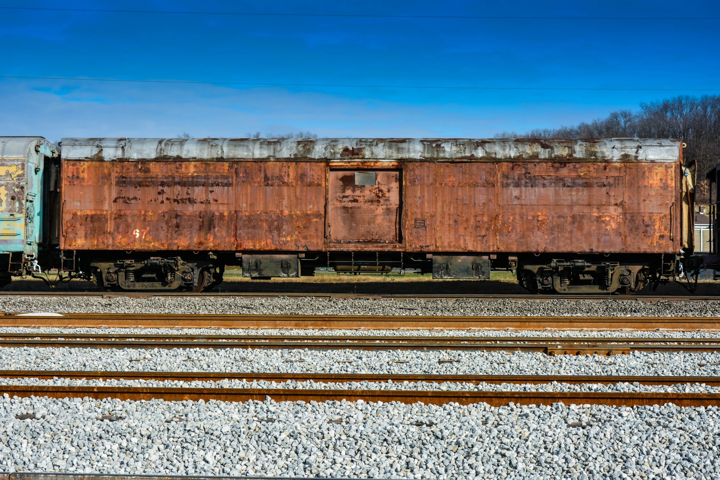 two train cars on a track with grass in the foreground