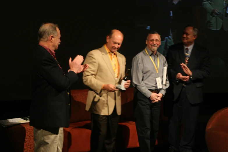 three men standing on stage talking to each other