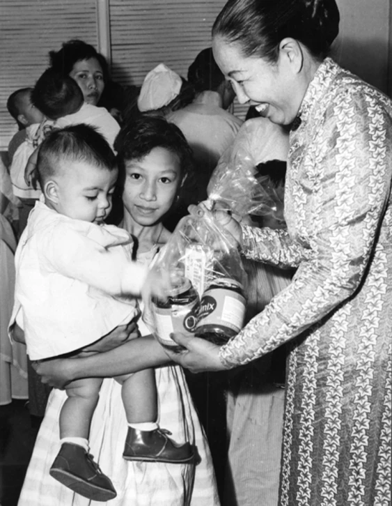 a woman is handing some gifts to a little girl