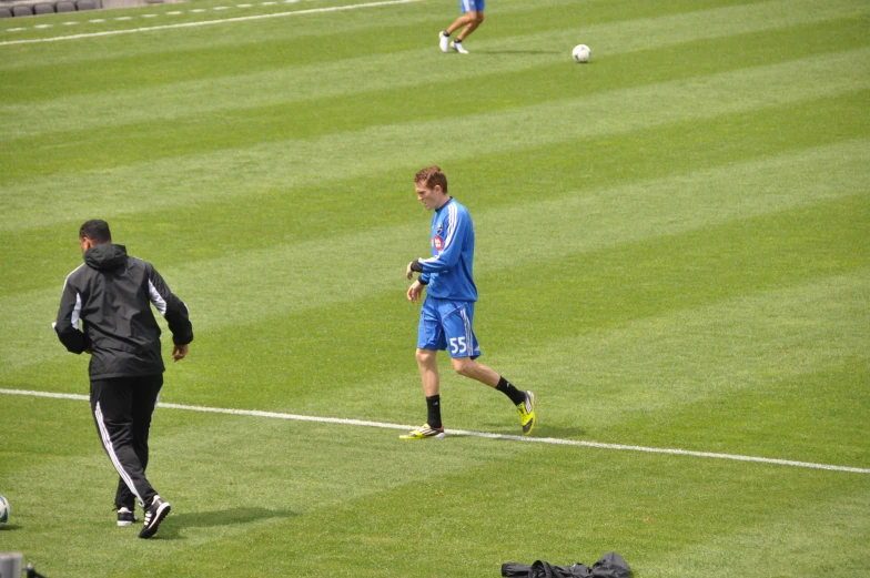 three soccer players on the field playing and a coach is watching