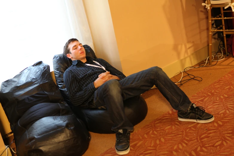 a young man sitting on a chair near a wall