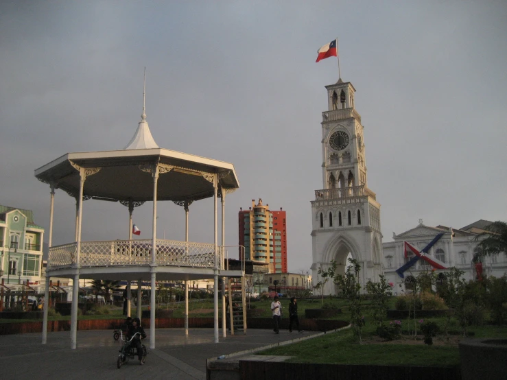 a white and brown clock tower sitting on the corner of a park