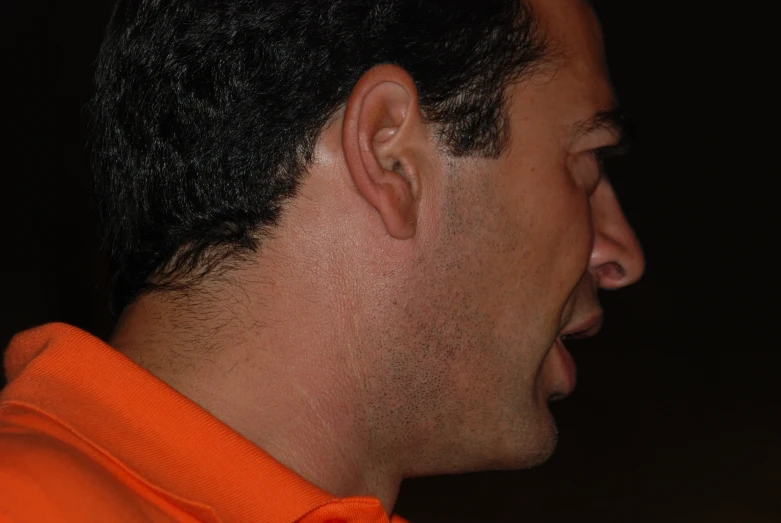 a man with a orange shirt with an open face