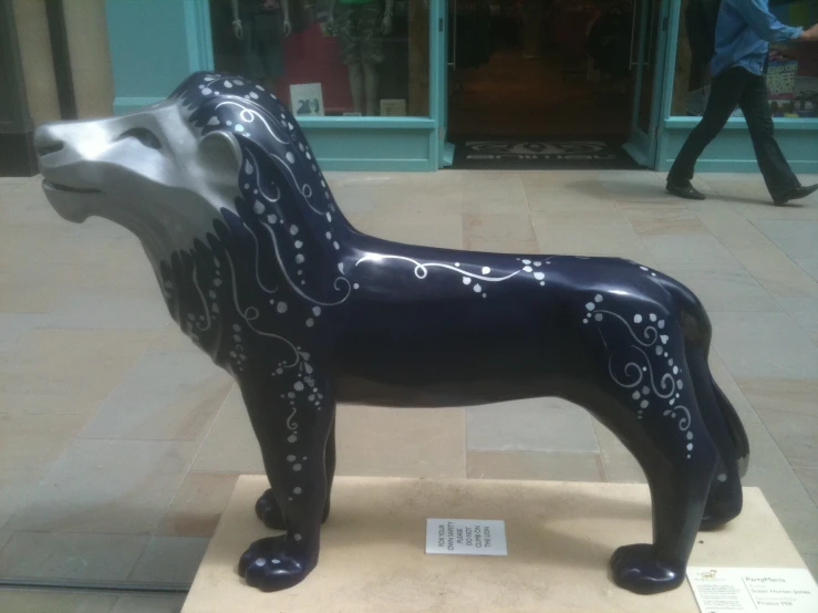 a statue of a black and white dog in front of a store