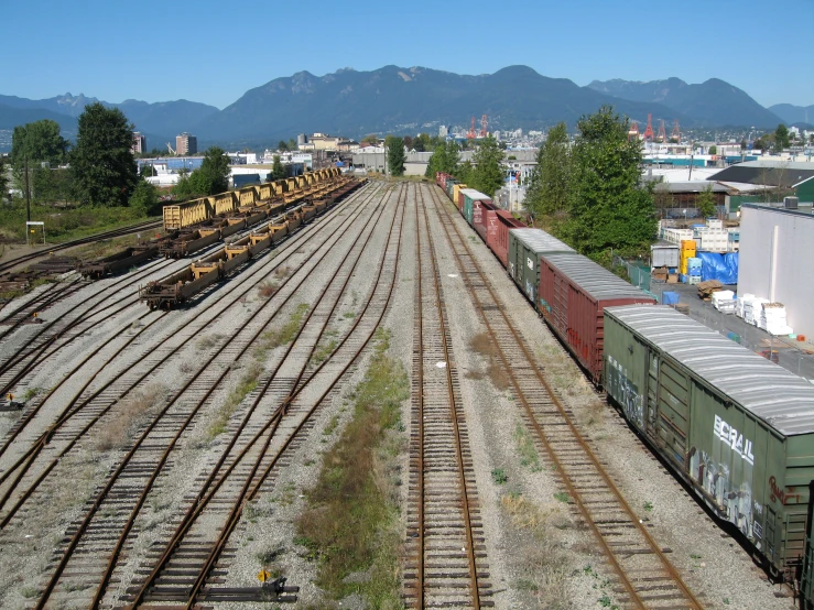 several trains on train tracks with buildings in the background