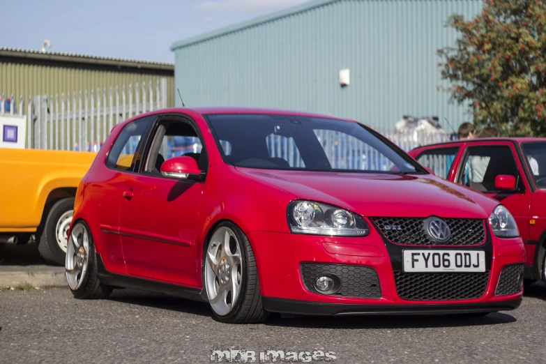 a red volkswagen car is shown parked in front of another yellow car