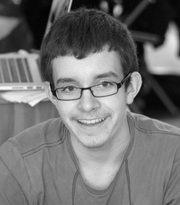 a black and white po shows a young man in glasses smiling