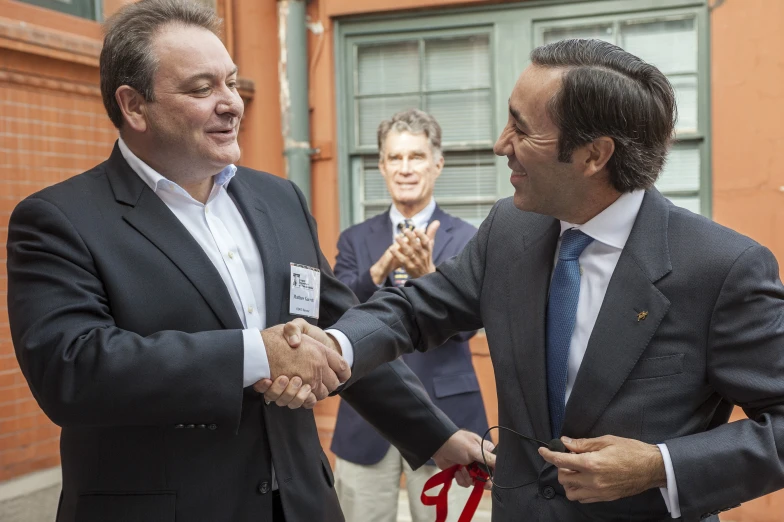 two men shaking hands outside of a building