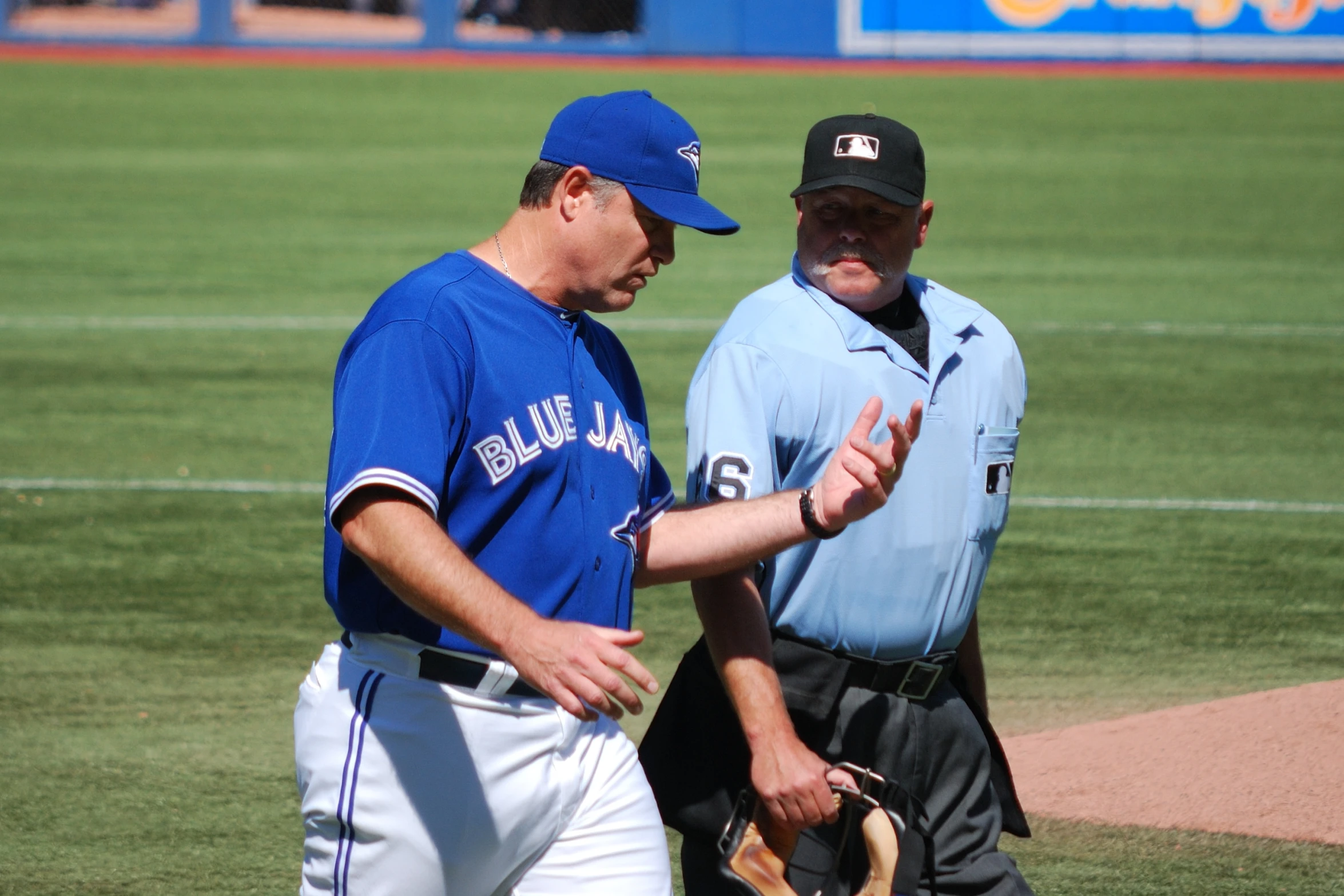 a baseball player talking with a coach on a field