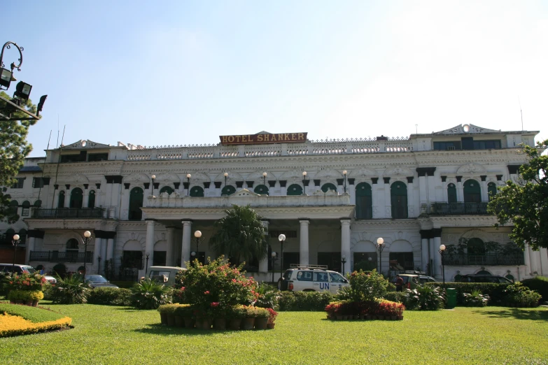 a large white building with arches and windows and greenery and lights