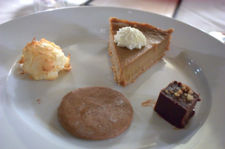 three different desserts on a white plate sitting on a table