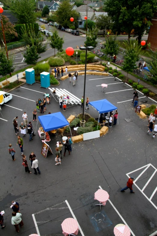 people walk past the food tents on a parking lot